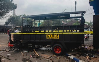 epa10218848 People walk past a torched police truck outside Kanjuruhan stadium in Malang, East Java, Indonesia, 02 October 2022. At least 127 people including police officers were killed mostly in stampedes after a clash between fans of two Indonesian soccer teams, according to the police.  EPA/SANDI SADEWA