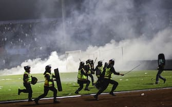 epa10218885 Police officers runs as they try to stop soccer fans from entering the pitch during a clash between fans at Kanjuruhan Stadium in Malang, East Java, Indonesia 02 October 2022. At least 127 people including police officers were killed mostly in stampedes after a clash between fans of two Indonesian soccer teams, according to the police.  EPA/H. PRABOWO