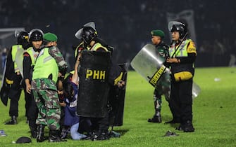 epa10218884 Police officers arrest a fan on the pitch during a clash between fans at Kanjuruhan Stadium in Malang, East Java, Indonesia 02 October 2022. At least 127 people including police officers were killed mostly in stampedes after a clash between fans of two Indonesian soccer teams, according to the police.  EPA/H. PRABOWO