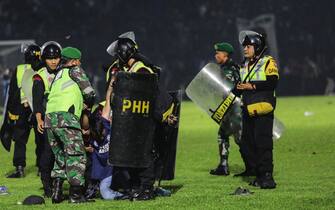 INDONESIA SOCCER RIOT epa10218884 Police officers arrest a fan on the pitch during a clash between fans at Kanjuruhan Stadium in Malang, East Java, Indonesia 02 October 2022. At least 127 people including police officers were killed mostly in stampedes after a clash between fans of two Indonesian soccer teams, according to the police. EPA/H. PRABOWO