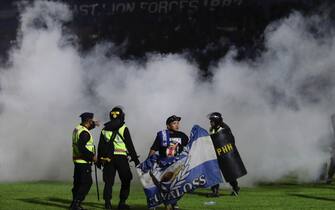 epa10218916 A soccer fan enters the pitch as police officers stand guard during a riot following a soccer match at Kanjuruhan Stadium in Malang, East Java, Indonesia, 01 October 2022 (issued on 02 October 2022). At least 127 people including police officers were killed after Indonesian soccer fans entered the pitch causing panic and stampede.  EPA/H. PRABOWO