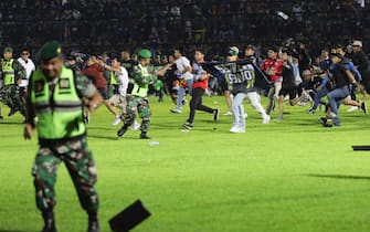 epa10218918 Soccer fans enter the pitch as military personnel try to stop them during a riot following a soccer match at Kanjuruhan Stadium in Malang, East Java, Indonesia, 01 October 2022 (issued on 02 October 2022).  At least 127 people including police officers were killed after Indonesian soccer fans entered the pitch causing panic and stampede.  EPA / H.  PRABOWO