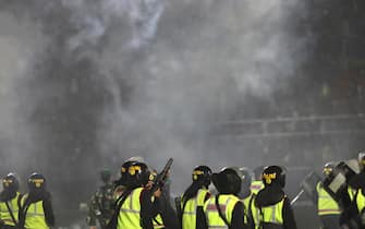 epa10218917 Police officers fire tear gas during a riot following a soccer match at Kanjuruhan Stadium in Malang, East Java, Indonesia, 01 October 2022 (issued on 02 October 2022). At least 127 people including police officers were killed after Indonesian soccer fans entered the pitch causing panic and stampede.  EPA/H. PRABOWO