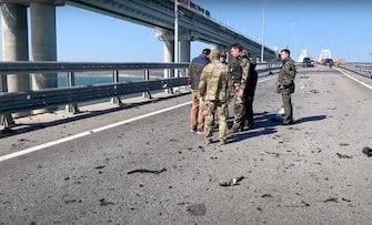 epa10230387 A still image taken from handout video provided by the Russian Investigative committee shows Russian investigators work on a collapsed part of the Kerch Strait bridge in Crimea, 08 October 2022. According to Russian authorities, "an explosion was set off at a cargo vehicle on the motorway part of the Crimean bridge on the side of the Taman peninsula, which set fire to seven fuel tanks of a train that was en route to the Crimean peninsula. Two motorway sections of the bridge partially collapsed. "  EPA / RUSSIAN INVESTIGATIVE COMMITEE HANDOUT HANDOUT EDITORIAL USE ONLY / NO SALES