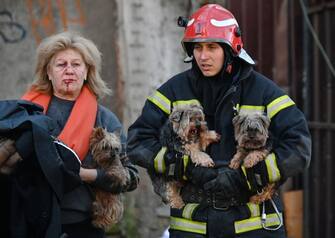 TOPSHOT - An emergency worker carries dogs as he escorts a local resident outside a partially destroyed multistorey office building after several Russian strikes hit the Ukrainian capital of Kyiv on October 10, 2022, amid Russia's invasion of Ukraine. - The head of the Ukrainian military said that Russian forces launched at least 75 missiles at Ukraine on Monday morning, with fatal strikes targeting the capital Kyiv, and cities in the south and west. (Photo by Sergei SUPINSKY / AFP) (Photo by SERGEI SUPINSKY/AFP via Getty Images)