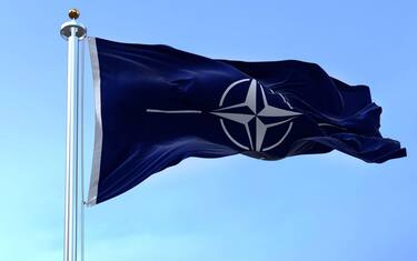 NATO (North Atlantic Treaty Organization) flag waving in the wind in a clear day. NATO is an international military alliance that constitutes a system