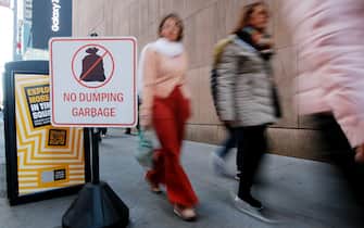 NEW YORK, NEW YORK - OCTOBER 18: People make their way next to No Dumping Garbage sign on October 18, 2022 in New York City. In an effort to deter rats and keep the area from seeming too dirty, New Yorkers will have to wait until 8 p.m. to dump their trash out. (Photo by Leonardo Munoz/VIEWpress)