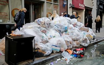 NEW YORK, NEW YORK - OCTOBER 18: People make their way past trash bags on October 18, 2022 in New York City. In an effort to deter rats and keep the area from seeming too dirty, New Yorkers will have to wait until 8 p.m. to dump their trash out. (Photo by Leonardo Munoz/VIEWpress)