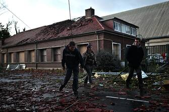 Local residents walk past a damaged house in a street full of fallen roof tiles in Bihucourt, northern France, on October 24, 2022 after a tornado hit the region. (Photo by Sameer Al-Doumy / AFP) (Photo by SAMEER AL-DOUMY/AFP via Getty Images)