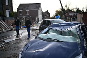 Local residents walk past a damaged house and destroyed cars in Bihucourt, northern France, on October 24, 2022 after a tornado hit the region. (Photo by Sameer Al-Doumy / AFP) (Photo by SAMEER AL-DOUMY/AFP via Getty Images)