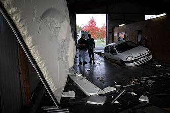 Owners of a automobile workshop look at damages in Beuzeville, northern France on October 24, 2022, after a tornado hit the region. (Photo by Lou BENOIST / AFP) (Photo by LOU BENOIST/AFP via Getty Images)