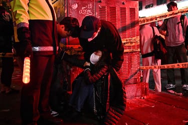 A woman is attended to as dozens of people suffered cardiac arrest in the popular nightlife district of Itaewon in Seoul on October 30, 2022. - Dozens of people suffered from cardiac arrest in the South Korean capital Seoul, after thousands of people crowded into narrow streets in the city's Itaewon neighbourhood to celebrate Halloween, local officials said. (Photo by Anthony WALLACE / AFP)