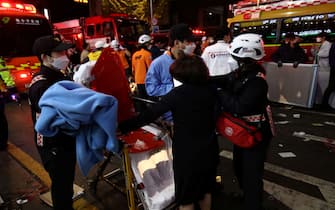 SEOUL, SOUTH KOREA - OCTOBER 30: Emergency services carry injured people after a stampede on October 30, 2022 in Seoul, South Korea. At least 50 people were reported to be receiving CPR after suffering from cardiac arrest in Seoul's Itaewon area as huge crowds of people stampeded at Halloween parties, according to authorities. (Photo by Chung Sung-Jun/Getty Images)