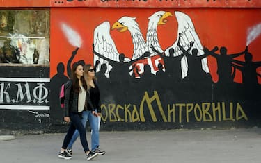 epa10279179 Women walk in front of a mural reading in Serbian language 'because there's no turning back' in the northern Serb-dominated part of ethnically divided town of Mitrovica, Kosovo, 01 November 2022. The Government of Kosovo will begin implementing a plan to eliminate the usage of Serbian car license plates. All owners of vehicles with Serbian number plates are warned and requested to visit any of the Vehicle Registration Centers and register their vehicles with RKS license plates. In the Serbian community of Kosovo, the RKS license plates are seen as unacceptable as they suggest the recognition of independence of the Republic of Kosovo.  EPA/DJORDJE SAVIC