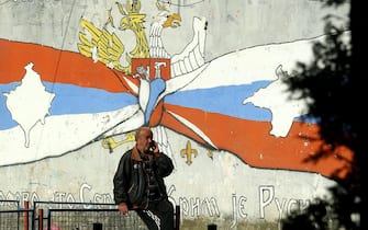 epa10279181 A man talks on the phone in front of a mural that shows Serbian (L) and Russian (R) flags with maps of Kosovo and Crimea in the northern, Serb-dominated part of ethnically divided town of Mitrovica, Kosovo, 01 November 2022. The Government of Kosovo will begin implementing a plan to eliminate the usage of Serbian car license plates. All owners of vehicles with Serbian number plates are warned and requested to visit any of the Vehicle Registration Centers and register their vehicles with RKS license plates. In the Serbian community of Kosovo, the RKS license plates are seen as unacceptable as they suggest the recognition of independence of the Republic of Kosovo.  EPA/DJORDJE SAVIC