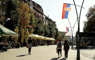 epa10279188 People walk in a street lined with Serbian flags in the northern, Serb-dominated part of ethnically divided town of Mitrovica, Kosovo, 01 November 2022. The Government of Kosovo will begin implementing a plan to eliminate the usage of Serbian car license plates. All owners of vehicles with Serbian number plates are warned and requested to visit any of the Vehicle Registration Centers and register their vehicles with RKS license plates. In the Serbian community of Kosovo, the RKS license plates are seen as unacceptable as they suggest the recognition of independence of the Republic of Kosovo.  EPA/DJORDJE SAVIC
