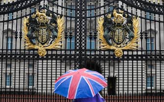 A person with an umbrella picturing the British national flag stands guard in front of Buckingham palace, central London, on September 8, 2022. - Fears grew on September 8, 2022 for Queen Elizabeth II after Buckingham Palace said her doctors were "concerned" for her health and recommended that she remain under medical supervision. The 96-year-old head of state -- Britain's longest-serving monarch -- has been dogged by health problems since last October that have left her with difficulties walking and standing. (Photo by Daniel LEAL / AFP) (Photo by DANIEL LEAL/AFP via Getty Images)
