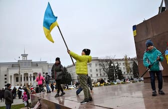 epa10303796 Children wave Ukrainian flags at the main square in the recently recaptured city of Kherson, Ukraine, 13 November 2022. Ukrainian troops arrived in Kherson on 11 November following the Russian troops' withdrawal from the city. Russian troops entered Ukraine on 24 February 2022 starting a conflict that has provoked destruction and a humanitarian crisis.  EPA/IVAN ANTYPENKO