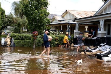 FORBES, AUSTRALIA - NOVEMBER 04: People carry sandbags through flood waters on November 04, 2022 in Forbes, Australia. Although rains have eased this week, many parts of NSW continued to be under flood warnings, as Premier Dominic Perrottet toured areas that have been inundated by recent rains. (Photo by Brendon Thorne/Getty Images)