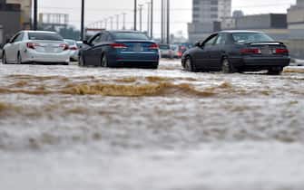 Cars drive through a flooded street following heavy rains in the Saudi coastal city of Jeddah on November 24, 2022, which delayed flights, forced school suspensions and closed the road to Mecca, Islam's holiest city. - Jeddah, a city of roughly four million people positioned on the Red Sea, is often referred to as the "gateway to Mecca", where millions perform the hajj and umrah pilgrimages each year. Winter rainstorms and flooding occur almost every year in Jeddah, where residents have long decried poor infrastructure. (Photo by Amer HILABI / AFP) (Photo by AMER HILABI/AFP via Getty Images)