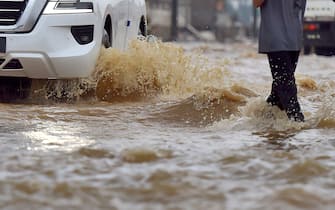 Men walk in a flooded street following heavy rains in the Saudi coastal city of Jeddah on November 24, 2022 which delayed flights, forced school suspensions and closed the road to Mecca, Islam's holiest city. - Jeddah, a city of roughly four million people positioned on the Red Sea, is often referred to as the "gateway to Mecca", where millions perform the hajj and umrah pilgrimages each year. Winter rainstorms and flooding occur almost every year in Jeddah, where residents have long decried poor infrastructure. (Photo by Amer HILABI / AFP) (Photo by AMER HILABI/AFP via Getty Images)