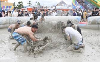 epa07728562 Festival-goers take a bath in a mud pool during the 22nd Boryeong Mud Festival on Daecheon beach in Boryeong City, South Korea, 20 July 2019. The festival runs from 19 to 28 July, with tourists flocking to the area to experience the alledged beneficial properties of the Boryeong mud, as well as for a variety of entertainment events.  EPA/KIM HEE-CHUL