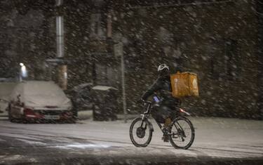 LONDON, UNITED KINGDOM - DECEMBER 11: A delivery man rides a bike on a snow-covered road during snowfall in London, United Kingdom on December 11, 2022. Officials announced that the most effective snowfall since 2013 is expected across the country. (Photo by Rasid Necati Aslim/Anadolu Agency via Getty Images)
