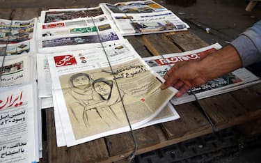 epa10274828 An Iranian man picks up a copy of Iranian daily newspaper Hammihan with a drawing featuring two Iranian female journalists Niloufar Hamedi and Elaheh Mohammadi with a title 'Ban the journalism' referring to the statement by the Tehran journalists' association against the prisoning journalists over covering protests in Iran, on display in a kiosk in Tehran, Iran, 30 October 2022. Niloufar Hamedi and Elaheh Mohammadi who are journalist for Iranian local daily newspaper were first two journalists who covered and published death of Mahsa Amini, and later were arrested and now are in prison. After Iranian government accused the two female journalists to conspiracy against the country, Tehran journalists' association published a statement as saying that 'journalism is not a crime'. Some Iranian journalists and photojournalists have been arrested and are in prison since the anti-government protests started in the country.  EPA/ABEDIN TAHERKENAREH