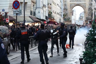 Protestors clashes with French riot police officers following a statement by French Interior Minister Gerald Darmanin (unseen) at the site where several shots were fired along rue d'Enghien in the 10th arrondissement, in Paris on December 23, 2022. - Three people were killed and three injured in a shooting in central Paris on December 23, 2022, police and prosecutors said, adding that the shooter, in his 60s, had been arrested. The motives of the gunman remain unclear, with two of the four injured left in a serious condition, the French officials said. (Photo by Thomas SAMSON / AFP) (Photo by THOMAS SAMSON/AFP via Getty Images)