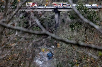 The wreck of a bus lies in the Lerez river after it plunged while crossing a bridge, killing four people, in Cerdedo-Cotobade, northwestern Spain, on December 25, 2022. - The accident occurred on December 24 night near Vigo and the border with Portugal. The regional La Voz de Galicia newspaper said the bus was carrying people visiting their loved ones jailed in Monterroso in central Galicia. Rescue operations had to be suspended overnight due to bad weather but resumed in the morning. (Photo by Brais Lorenzo / AFP) (Photo by BRAIS LORENZO/AFP via Getty Images)
