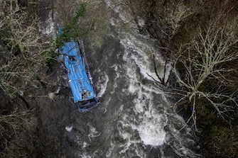 TOPSHOT - The wreck of a bus lies in the Lerez river after it plunged while crossing a bridge, killing four people, in Cerdedo-Cotobade, northwestern Spain, on December 25, 2022. - The accident occurred on December 24 night near Vigo and the border with Portugal. The regional La Voz de Galicia newspaper said the bus was carrying people visiting their loved ones jailed in Monterroso in central Galicia. Rescue operations had to be suspended overnight due to bad weather but resumed in the morning. (Photo by Brais Lorenzo / AFP) (Photo by BRAIS LORENZO/AFP via Getty Images)