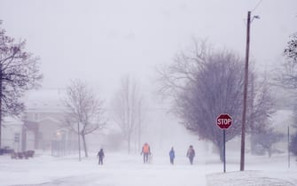 FLINT, MICHIGAN-DECEMBER 23-A family walks through a neighborbood during a winter snow storm affecting most of the USA, in Flint, MI on December 23, 2022. (Photo by Katie McTiernan/Anadolu Agency via Getty Images)