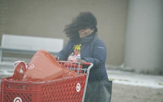 FLINT, MICHIGAN-DECEMBER 23-Last minute holiday shoppers rush to their cars to escape the high wind gusts and frigid temperatures of a winter storm affecting most of the USA, in Flint, MI on December 23, 2022. (Photo by Katie McTiernan/Anadolu Agency via Getty Images)