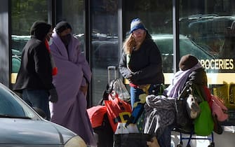 ORLANDO, FLORIDA, UNITED STATES - DECEMBER 24: A group of homeless people keep warm with blankets and winter clothing in front of a downtown business on December 24, 2022 in Orlando, Florida. Freezing cold weather arrived in Central Florida on Christmas Eve and is expected to continue all weekend. According to the US National Weather Service, Orlando could see the coldest Christmas since 1983. (Photo by Paul Hennessy/Anadolu Agency via Getty Images)