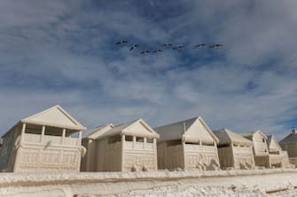 Geese fly over frozen homes in the waterfront community of Crystal Beach in Fort Erie, Ontario, Canada, on December 28, 2022, following a massive snow storm that knocked out power in the area to thousands of residents.  (Photo by Cole Burston/AFP) (Photo by COLE BURSTON/AFP via Getty Images)