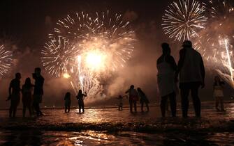SANTOS, BRAZIL - JANUARY 01: Brazilians celebrate during fireworks marking the start of the New Year at Gonzaga beach on January 1, 2023 in Santos, Brazil. The funeral for Brazilian football icon Edson Arantes do Nascimento, better known as Pele, will be held in the city at Urbano Caldeira Stadium on January 2nd. (Photo by Mario Tama/Getty Images)