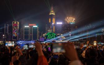People watching Fireworks display over building on Hong Kong Island, 2023 display on the Hong Kong Convention and Exhibition Center to mark the arrival of 2023 on January 1, 2023 in Hong Kong, China. (Photo by Vernon Yuen/NurPhoto)