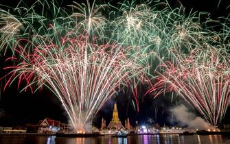 TOPSHOT - This photograph taken on January 1, 2023 shows a fireworks show over Wat Arun Buddhist temple on the Chao Phraya River during New Year celebrations in Bangkok. (Photo by Jack TAYLOR / AFP) (Photo by JACK TAYLOR/AFP via Getty Images)