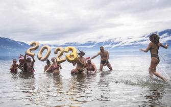 epa10385200 Swimmers take part in the New Year's dip in the Lago Maggiore in Tenero, Switzerland, 01 January 2023.  EPA/SAMUEL GOLAY