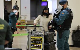 A civil guard gives indications to a passenger of a flight from Beijing after landing at the Adolfo Suarez Madrid-Barajas airport in Barajas, on the outskirts of Madrid, on December 31, 2022. - The first flight from China after the reinstatement by Spain of health controls  on passengers from that country, in the midst of an explosion of covid cases, arrived in Madrid today evening. The passengers of the Air China CA 907 flight had to undergo temperature controls, present a negative covid test or prove that they were immunized with one of the vaccines approved in Spain upon arrival at Barajas, causing a scene not seen in months at the Madrid airport. (Photo by Pierre-Philippe Marcou / AFP) (Photo by PIERRE-PHILIPPE MARCOU/AFP via Getty Images)