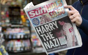 Paris, FRANCE:  A man reads, 13 January 2005 in Paris, the British tabloid The Sun featuring Harry, 20, the younger son of Prince Charles and the late Princess Diana, wearing a khaki uniform with an armband emblazoned with a swastika, emblem of the German WWII Nazi Party. The photographs in The Sun newspaper triggered outrage, especially from the Jewish community which pointed out that they appear as the royal family prepares to lead commemorations of the 60th anniversary of the Holocaust. AFP PHOTO GABRIEL BOUYS  (Photo credit should read GABRIEL BOUYS/AFP via Getty Images)