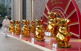 SHANGHAI, CHINA - JANUARY 12: A pedestrian walks by gold rabbit installations in the street ahead of the Chinese Lunar New Year, the Year of the Rabbit, on January 12, 2023 in Shanghai, China. (Photo by VCG/VCG via Getty Images)