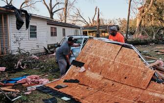 USA WEATHER TORNADO ALABAMA epa10402421 Arthur Threatt (L) and Rob Auxtin (R) try to remove debris on top of a car near tornado destroyed trailer homes in Mount Vernon, Alabama, USA on 12 January 2023. EPA/DAN ANDERSON