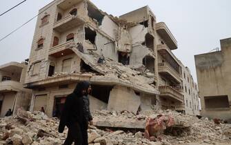 Two men walk past a heavily damaged building following an earthquake in the town of Sarmada in the countryside of the northwestern Syrian Idlib province, early on February 6, 2023. - A 7.8-magnitude earthquake hit Turkey and Syria on February 6, killing hundreds of people as they slept, levelling buildings, and sending tremors that were felt as far away as the island of Cyprus and Egypt. (Photo by Mohammed AL-RIFAI / AFP) / The erroneous mention[s] appearing in the metadata of this photo by Mohammed AL-RIFAI has been modified in AFP systems in the following manner: [the town Sarmada] instead of [Zardana]. Please immediately remove the erroneous mention[s] from all your online services and delete it (them) from your servers. If you have been authorized by AFP to distribute it (them) to third parties, please ensure that the same actions are carried out by them. Failure to promptly comply with these instructions will entail liability on your part for any continued or post notification usage. Therefore we thank you very much for all your attention and prompt action. We are sorry for the inconvenience this notification may cause and remain at your disposal for any further information you may require. (Photo by MOHAMMED AL-RIFAI/AFP via Getty Images)
