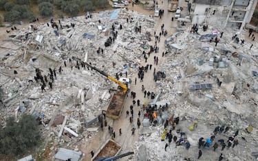 IDLIB, SYRIA - FEBRUARY 06: An aerial view of a collapsed buildings as personnel and civilians conduct search and rescue operations in Idlib, Syria after 7.7 and 7.6 magnitude earthquakes hits Turkiye's Kahramanmaras, on February 06, 2023. As a result of the earthquake, at least 968 people lost their lives in different parts of Syria, and more than 2,403 were injured. Early Monday morning, a strong 7.7 earthquake, centered in the Pazarcik district, jolted Kahramanmaras and strongly shook several provinces, including Gaziantep, Sanliurfa, Diyarbakir, Adana, Adiyaman, Malatya, Osmaniye, Hatay, and Kilis. Later, at 13.24 p.m. (1024GMT), a 7.6 magnitude quake centered in Kahramanmaras' Elbistan district struck the region. Earthquakes had affected several provinces in Syria's Idlib, Aleppo, Hama, Latakia, Tartus and Raqqa. (Photo by Izzeddin Kasim/Anadolu Agency via Getty Images)