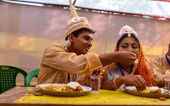 A groom is seen helping his bride to have food ahead of mass marriage ceremony on valentines day in Kolkata , India , on 14 February 2023 . (Photo by Debarchan Chatterjee/NurPhoto via Getty Images)