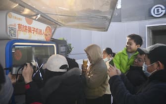 **CHINESE MAINLAND, HONG KONG, MACAU AND TAIWAN OUT** People watch the robot making jianbing guozi, a kind of stuffed pancake, at the exit of Niujie subway station in Beijing, China, 19 February, 2023. (Photo by ChinaImages/Sipa USA)