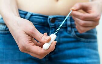 Woman holding tampon in her hands.