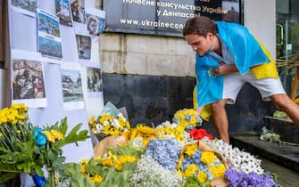 epa10487428 A man lays flowers during a vigil for Ukraine in Denpasar, Bali, 24 February 2023. Ukrainians in Bali marked the first anniversary of the Russian invasion of Ukraine with a vigil outside the Ukraine Consulate in Denpasar.  EPA/MADE NAGI