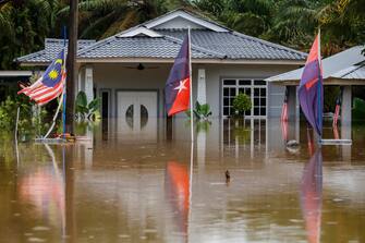 epaselect epa10501877 Malaysian and Johor flags flutter in front of a flooded house in Yong Peng, Johor, Malaysia, 04 March 2023. According to state media, more than 33,000 people were evacuated in four states affected by the floods.  EPA/FAZRY ISMAIL